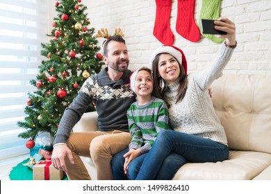 Woman taking selfie with family on smartphone at home during Christmas holiday - Powered by Shutterstock