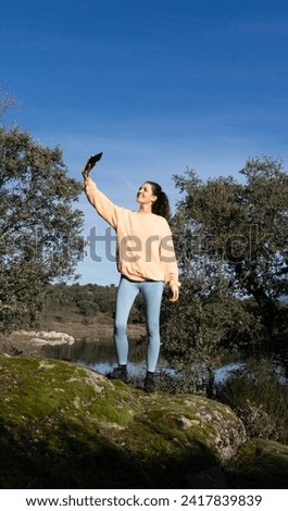 Woman taking a selfie with her cell phone in nature dressed in peach color