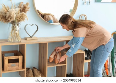 Woman taking shoes from stand in hall
