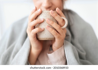 Woman taking a sip of tea from the mug during winter - Shutterstock ID 2010368933