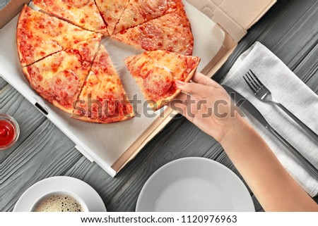 Woman taking slice of tasty pizza from box, top view