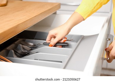 Woman taking spoon from drawer in kitchen, closeup