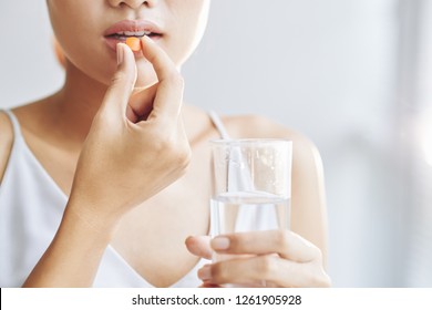 Woman taking tablet with glass of fresh water