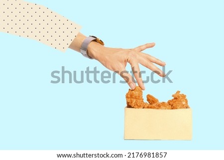 Woman taking tasty deep fried chicken wing from paper box on light blue background
