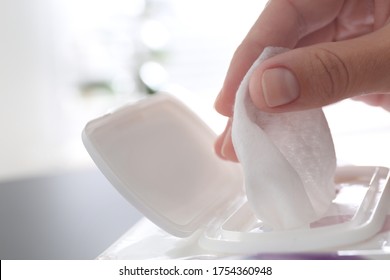Woman taking wet wipe from pack on blurred background, closeup