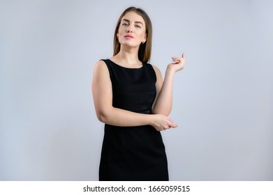 A Woman Is Talking To The Camera. Photo Of A Pretty Girl In A Black Dress On A White Background.