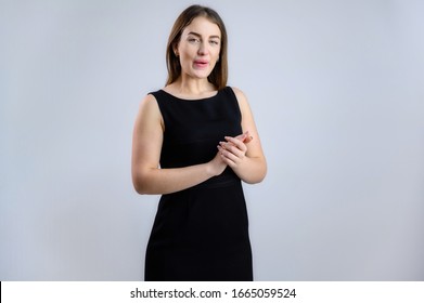 A Woman Is Talking To The Camera. Photo Of A Pretty Girl In A Black Dress On A White Background.