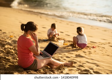 Woman Talking To Clients On Phone, Working On Laptop. Kids Playing With Beach Sand.