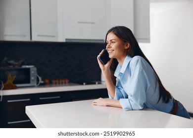 Woman talking on cell phone while sitting at kitchen table in cozy home environment - Powered by Shutterstock