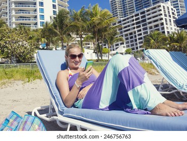 Woman Talking On Her Cell Phone While Lounging On The Beach
