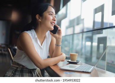 Woman talking on mobile phone while sitting in cafe, Smiling girl having talking conversation with cell phone in coffee shop.