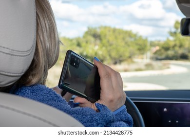 A Woman Is Talking On A Mobile Phone In The Car. Driver With Mobile Phone In Hand. The Concept Of Safe Driving. A Woman Driving Texts. Dangerous Use Of A Mobile Phone While Driving.