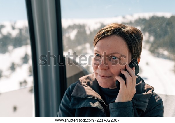 Woman\
talking on mobile phone while driving in gondola overhead cable car\
at Zlatibor mountain in winter, selective\
focus