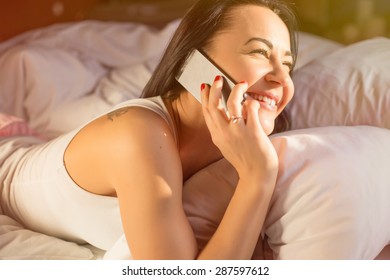 Woman Talking On Phone In Bed