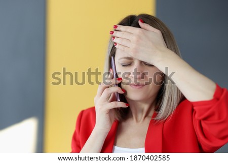 Woman is talking on phone and holding her forehead with her hand. Memory impairment forgetfulness concept