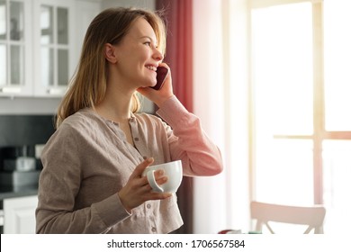 Woman talking on the phone in the kitchen at home