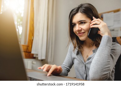 woman talking on the phone while working on computer in desk office. Searching on internet