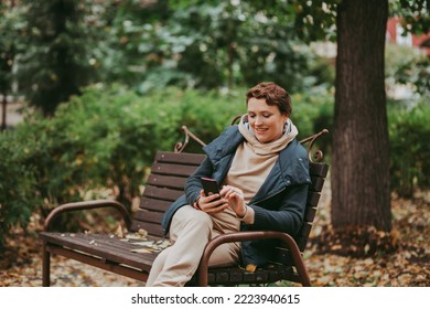 Woman talking on smartphone while sitting in autumn park