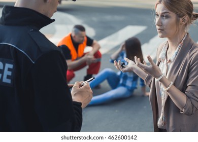 Woman Talking With The Police Officer With The Casualty Of Car Accident At The Background