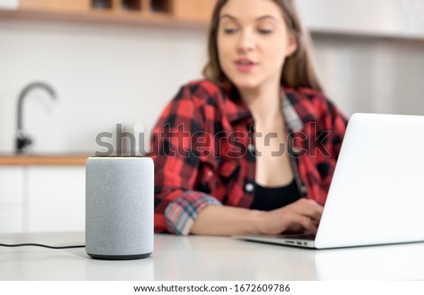 Woman talking to smart speaker. Intelligent
assistant in smart home
system.