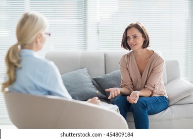 Woman talking to therapist on sofa at home - Powered by Shutterstock