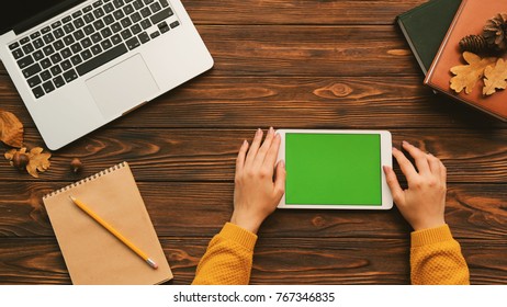 Woman Tapping , Swiping, Zooming On The White Tablet Device With Green Screen On The Woosen Table With Laptop And Notebooks. Studying, Surfing Internet. Chroma Key. Top View