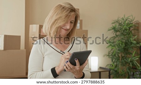 Woman tapping tablet with hands while checking packages and parcels in a smallbusiness building; entrepreneurial planning contentment.