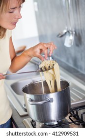 Woman Tasting Pasta In A Kitchen