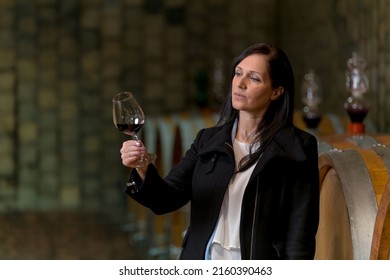 Woman tasting red wine in a old traditional cellar - Shutterstock ID 2160390463