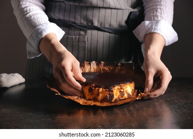 Woman With Tasty Basque Burnt Cheesecake In Kitchen