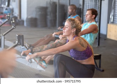 Woman with tattoos exercising on rowing machine, part of circuit training warmup cardio session - Powered by Shutterstock