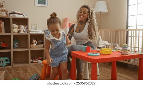 Woman with tattoos and toddler playing in bright kindergarten playroom, surrounded by toys and shelves filled with stuffed animals, enjoying a happy indoor moment together. - Powered by Shutterstock