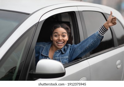 Woman Taxi Driver And Great Mood On Active Work. Happy Young Success African American Female Sitting In Silver Car And Showing Thumb Up Hand Gesture In Open Window Enjoying Driving, Free Space