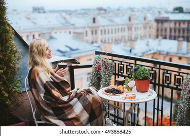 Woman With Tea Sheltered Blanket Breakfast On The Balcony Overlooking The City