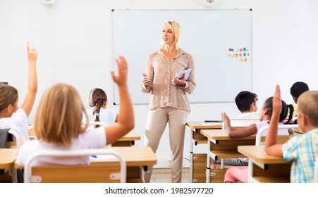 Woman teacher explaining studying material to tweens during lesson in elementary school, - Powered by Shutterstock