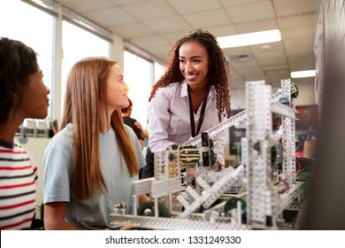 Woman Teacher With Female College Students Building Machine In Science Robotics Or Engineering Class