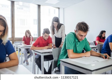 A Woman Teacher Helping To A Student During An Exam.