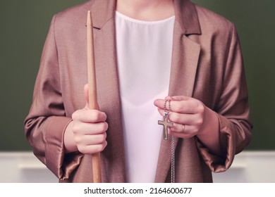 Woman Teacher Holding Religious Symbol Catholic Cross On School Blackboard In The Classroom