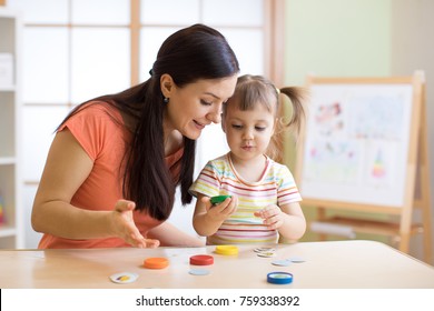 Woman teacher play with preschooler child in day care center.