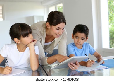 Woman Teaching Class To School Children With Digital Tablet