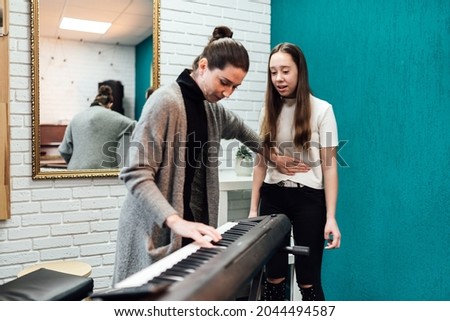 Woman teaching her student to sing while accompanementing on electronic piano