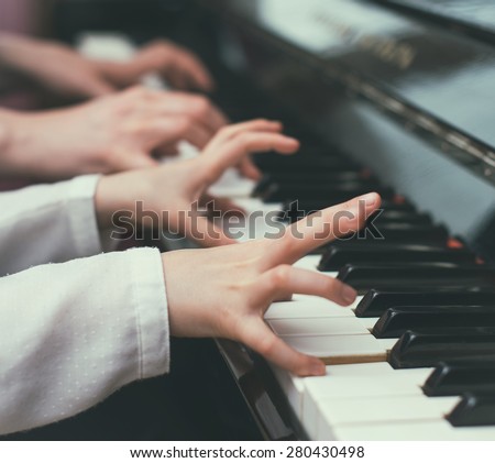 Woman teaching little girl to play the piano.