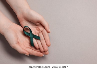 Woman with teal ribbon on grey background, top view with space for text. Ovarian cancer and gynecological disorders awareness - Powered by Shutterstock