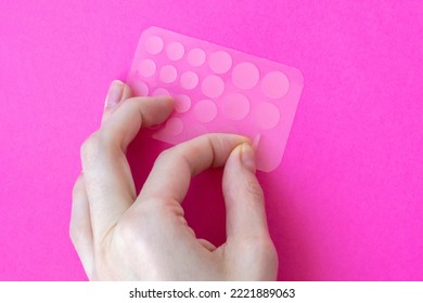 Woman Tears Off An Acne Patch To Stick On Her Skin. Acne Patches On A Pink Background View From Above