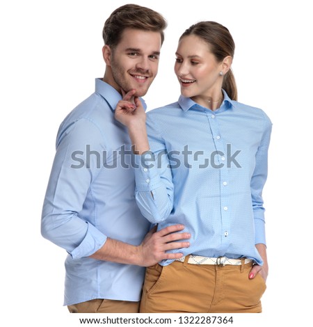 woman teases man by touching his chin while he hugs her on white background