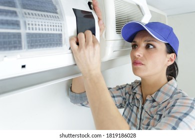 Woman Technician Fixing An Air Conditioning System