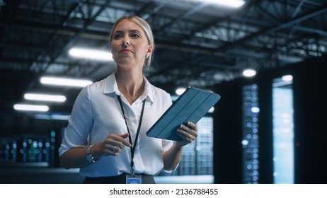 Woman IT Technician Works On Tablet Computer In Big Data Center At Night. She Runs Diagnostics And Maintenance, Sets System Up. Cloud Service, Server Transfer And Analytics Concept