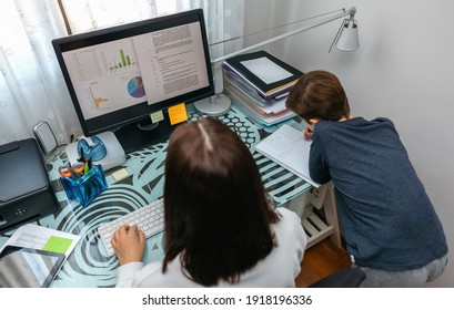 Woman teleworking at home while her son studies next to her