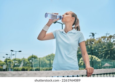 Woman, tennis and drinking water for hydration after workout, exercise or intense training on court. Sporty female with bottle for refreshing drink, thirst or stay hydrated during sports exercising - Powered by Shutterstock