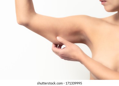 Woman testing the flabby muscle under her arm pulling it down with her hand as she checks for muscle tone or weight gain